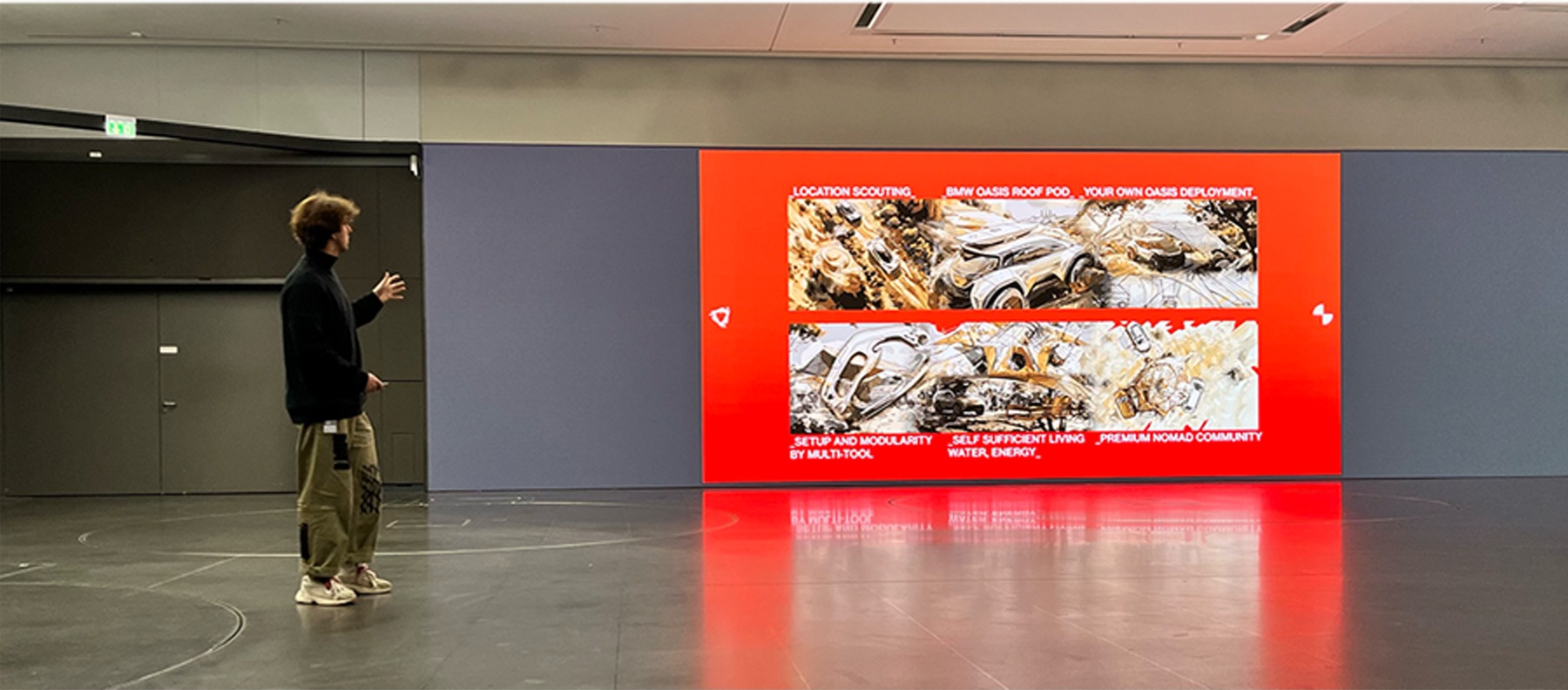 Presentation space with a visitor viewing a red setup and modularity display panel