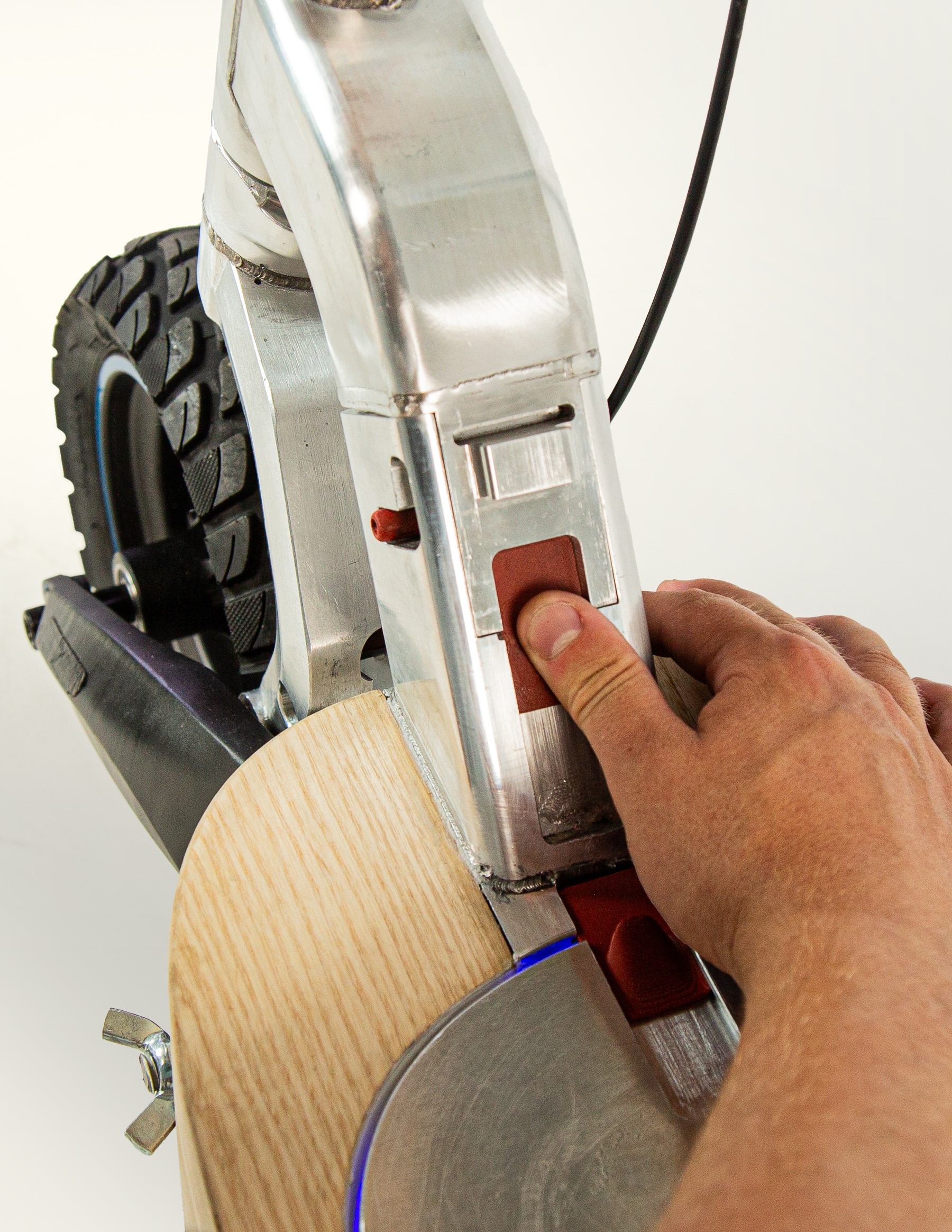 Hand pressing the fold-release button at the steering neck