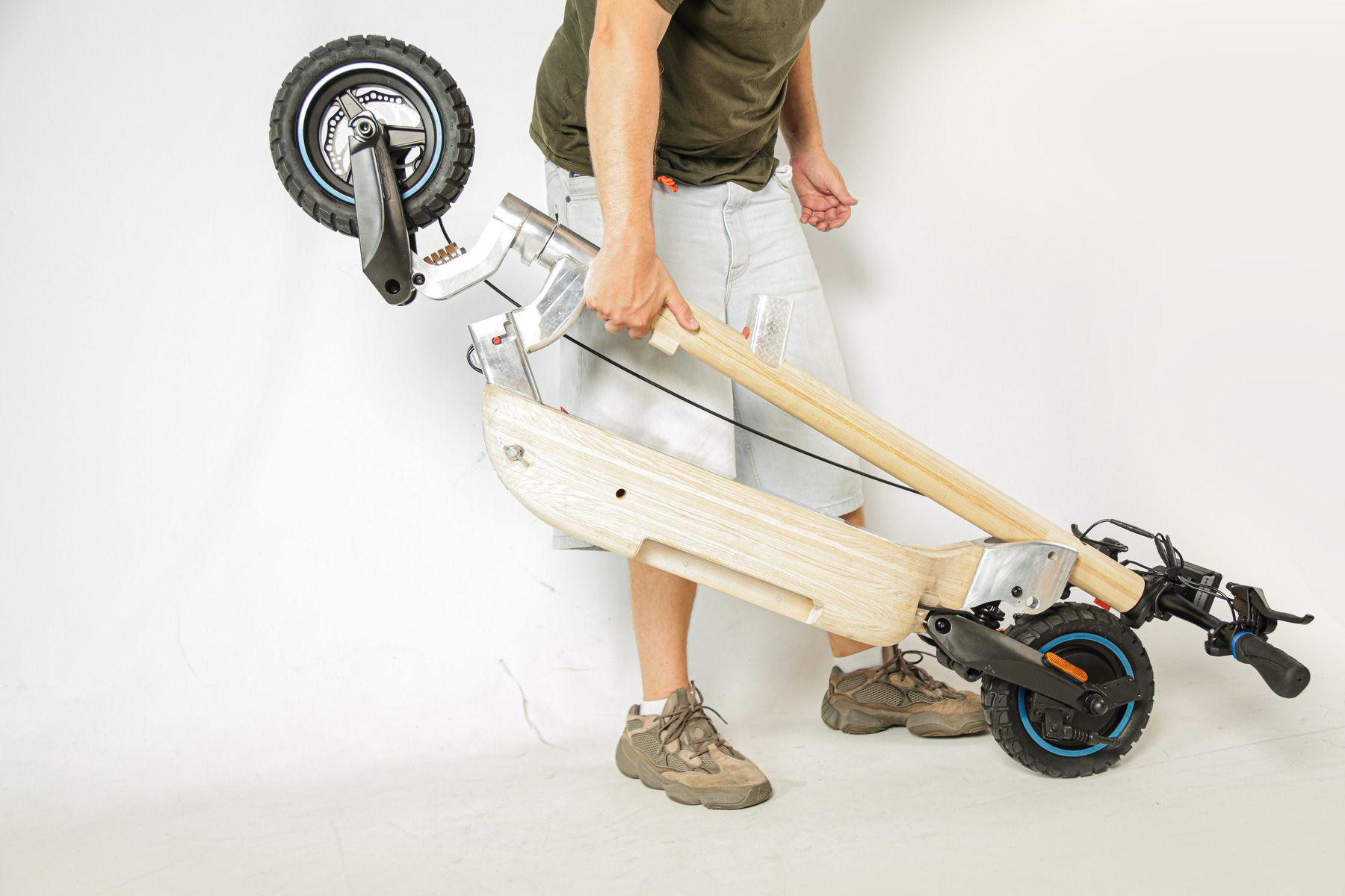 Person carrying the folded scooter by its handle