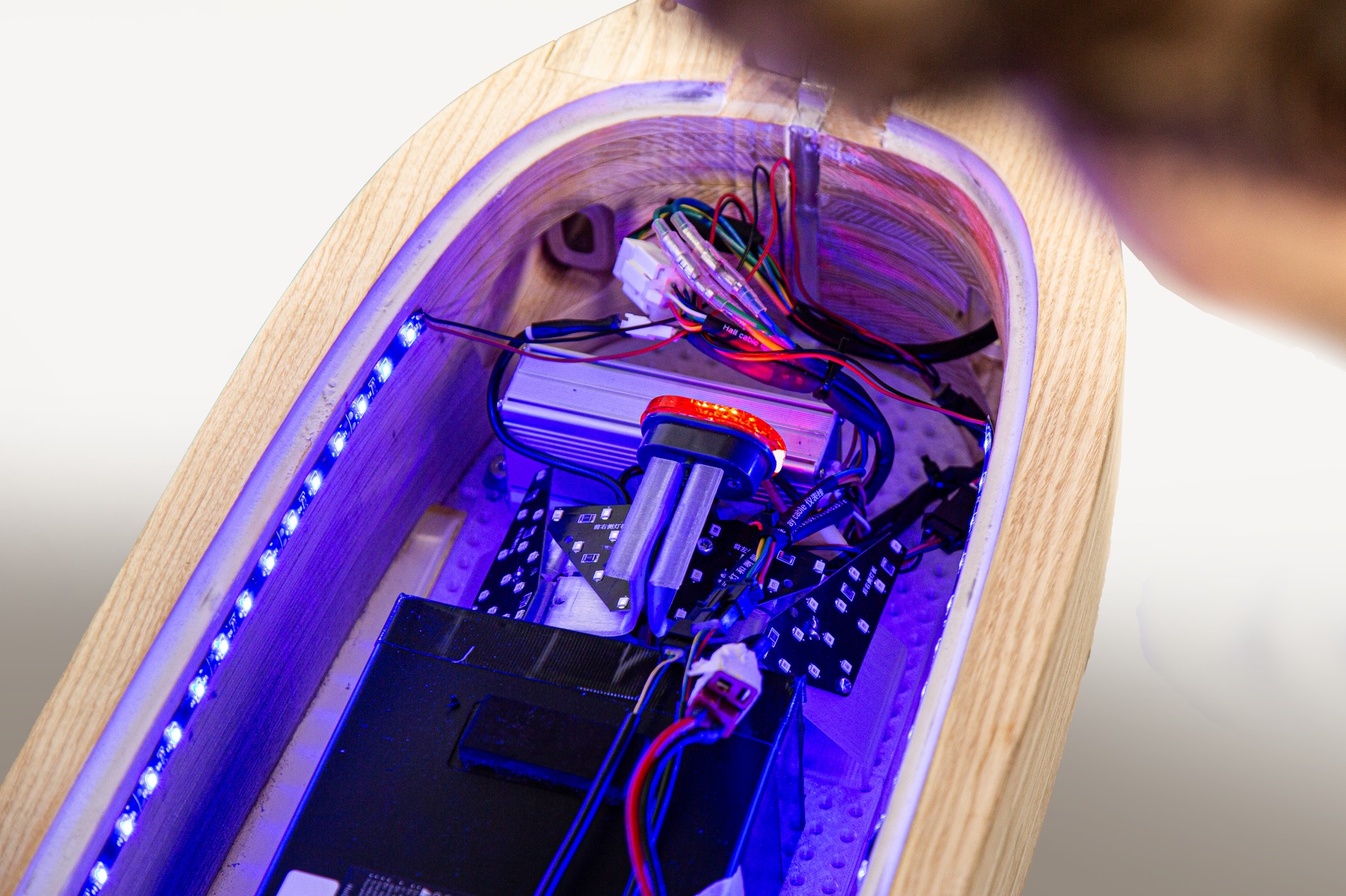 Close detail of the deck's internal wiring and battery pack under purple light