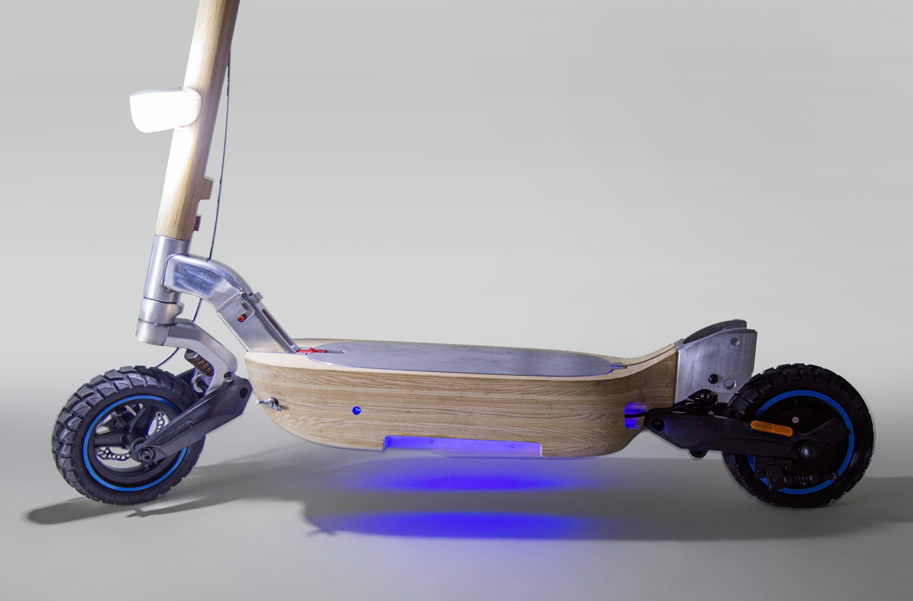 Scooter side view with underside light glowing, gray studio background