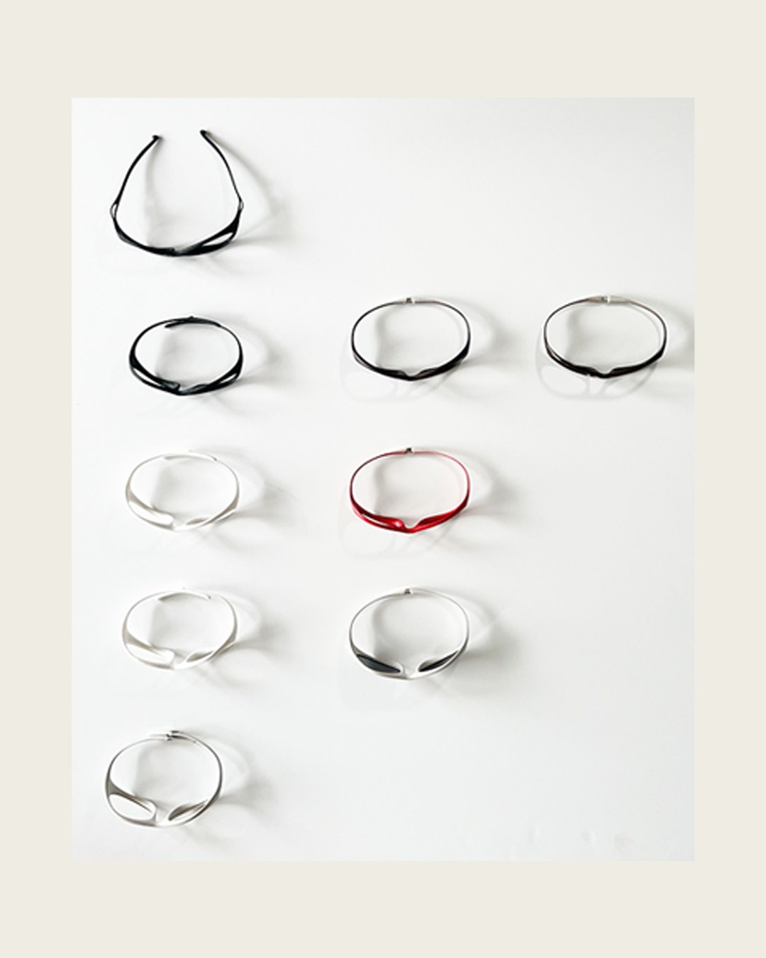 Grid of frame silhouette prototypes in black, white and red on a pegboard