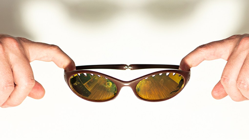 Close-up of hands holding the folded frame with amber mirrored lenses