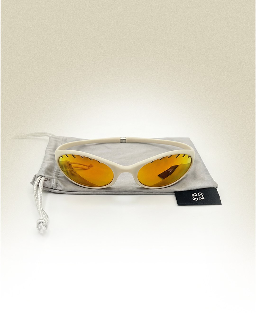 White frame with amber lenses resting in its drawstring pouch