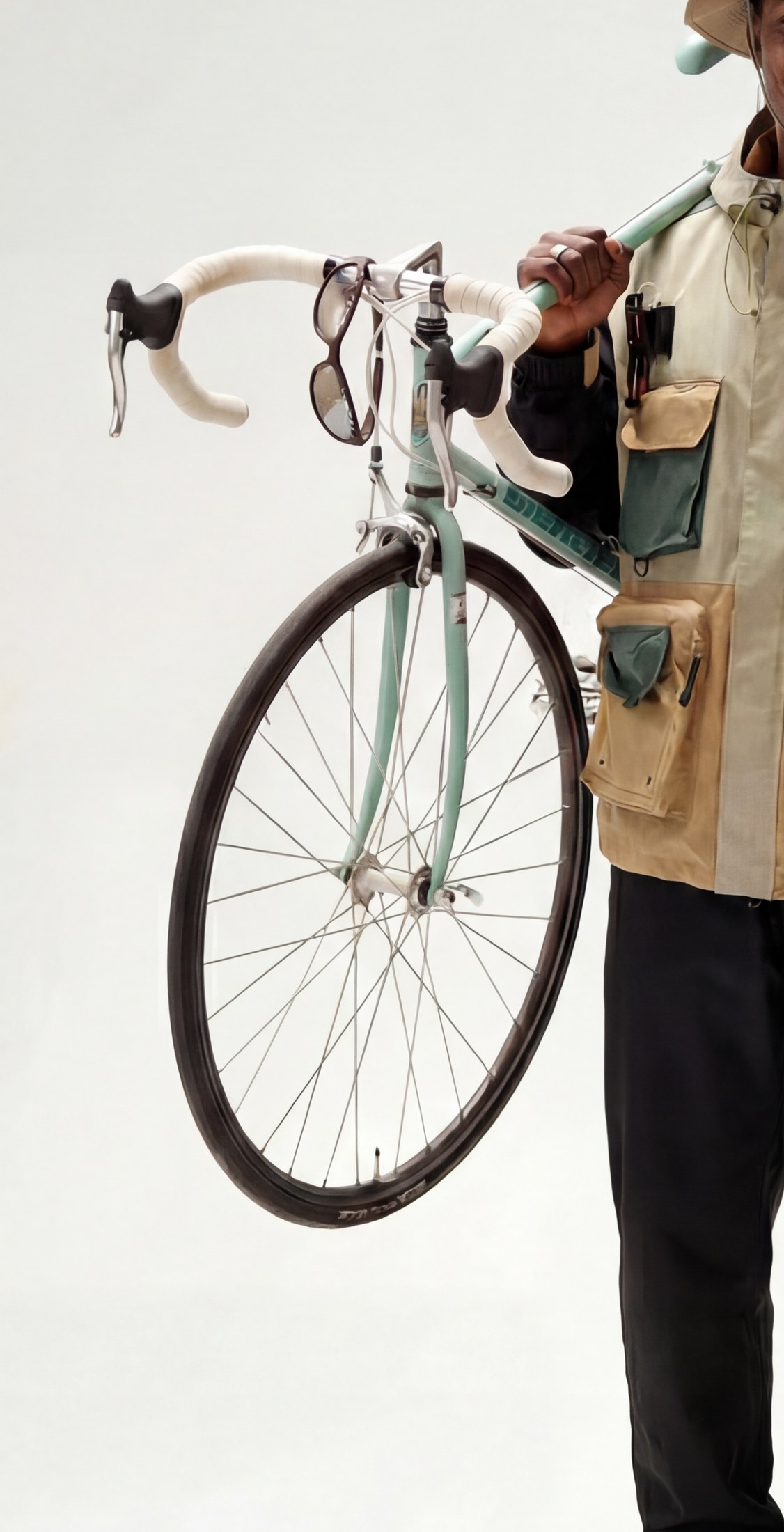Frame's glasses hooked onto a bicycle handlebar, carried alongside a touring bag