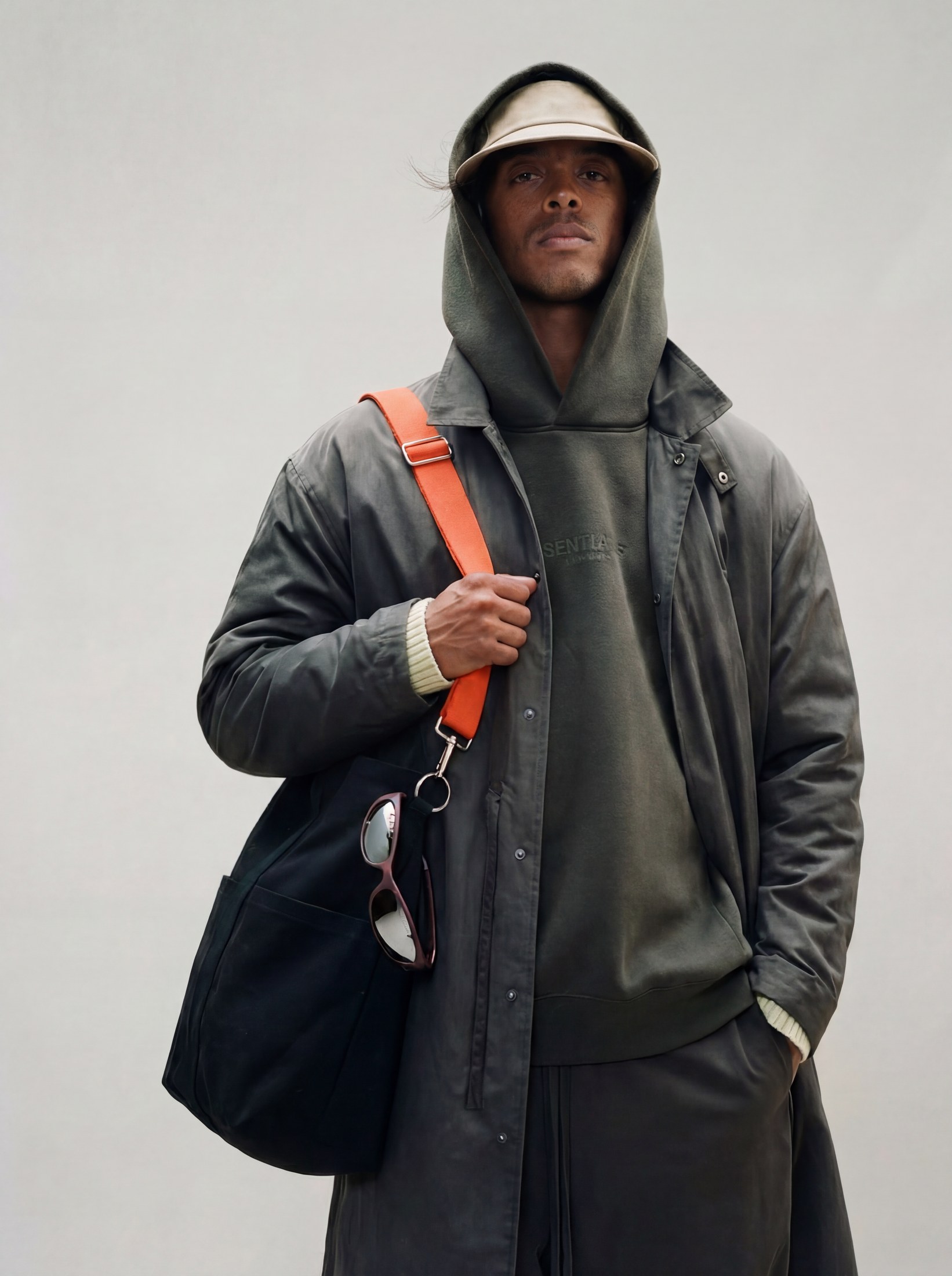Lifestyle shot of the frame clipped to a bag strap, worn with a hooded jacket
