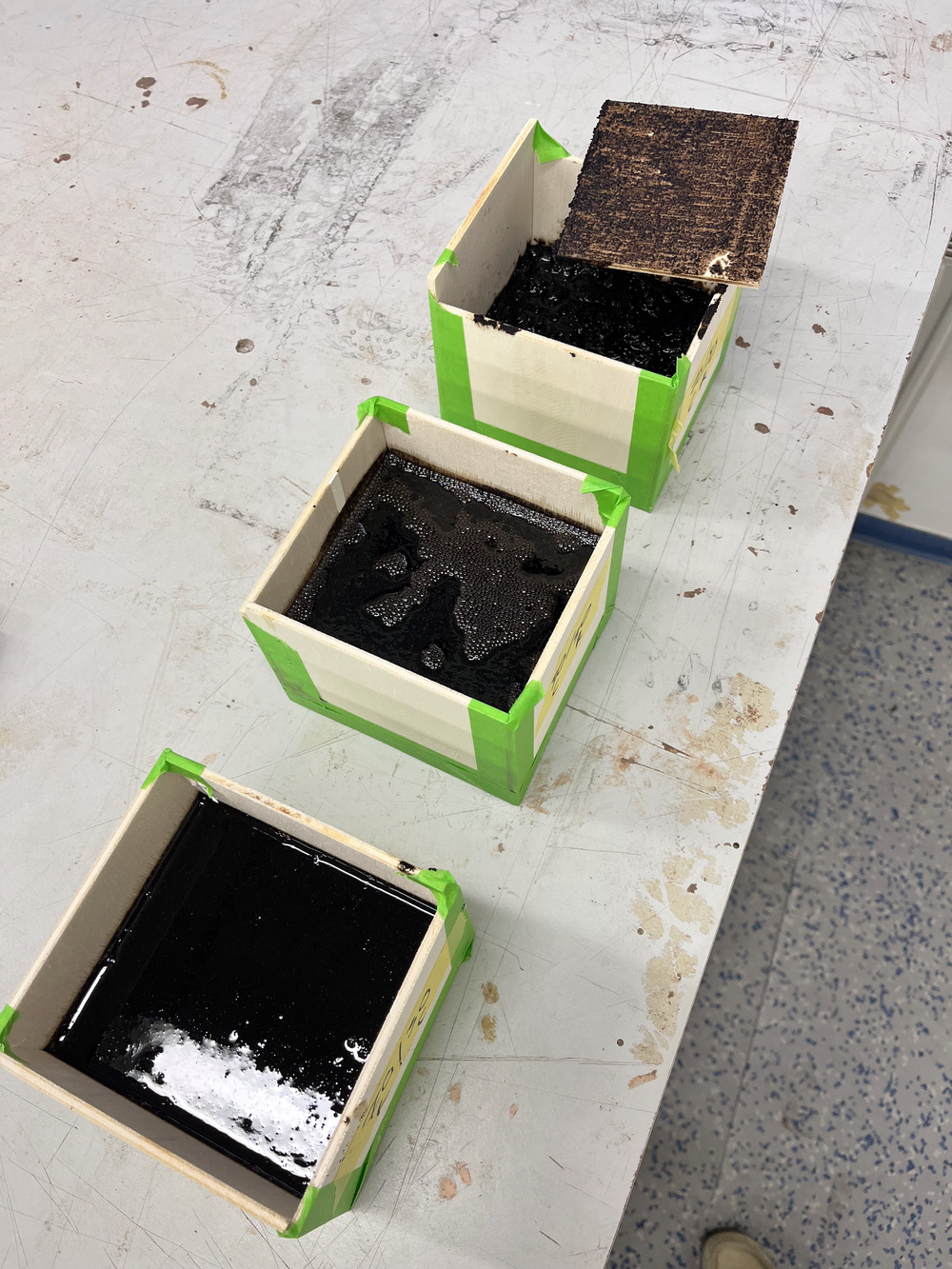 Coffee-ground composite test panels curing in wooden molds on a workshop bench
