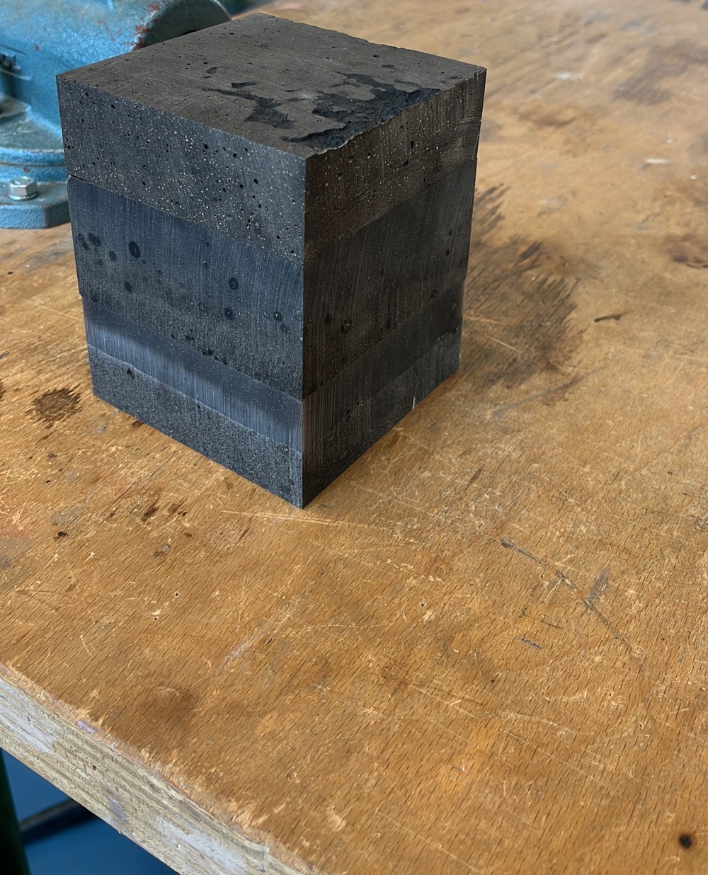 Pressed coffee-ground composite block held in a bench vice